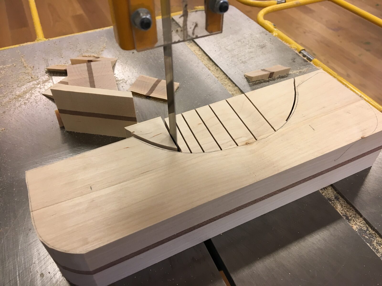 Lagerlimmad träplatta sågas till en klubblogga i bandsåg