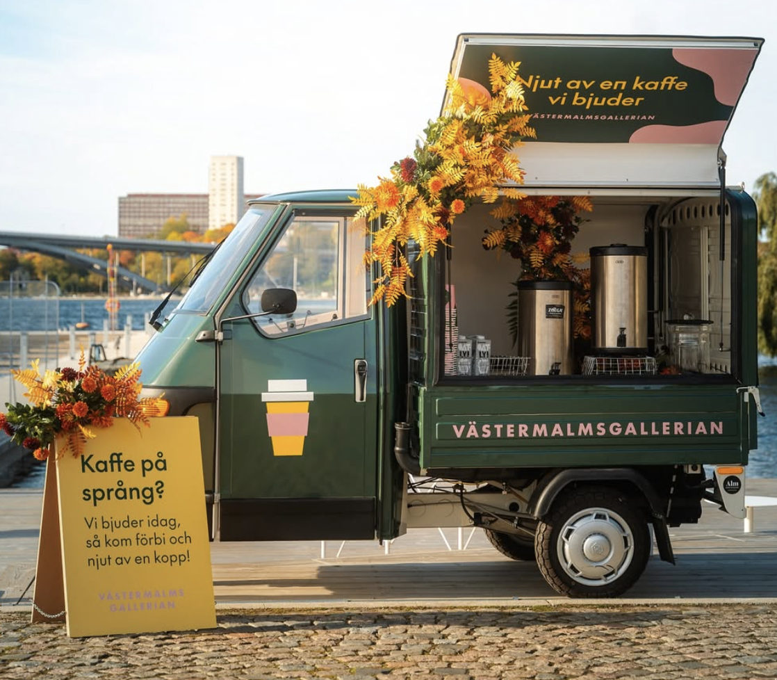 Grön kaffevagn på tre hjul dekorerad med höstblommor, byggd för Västermalmsgallerian