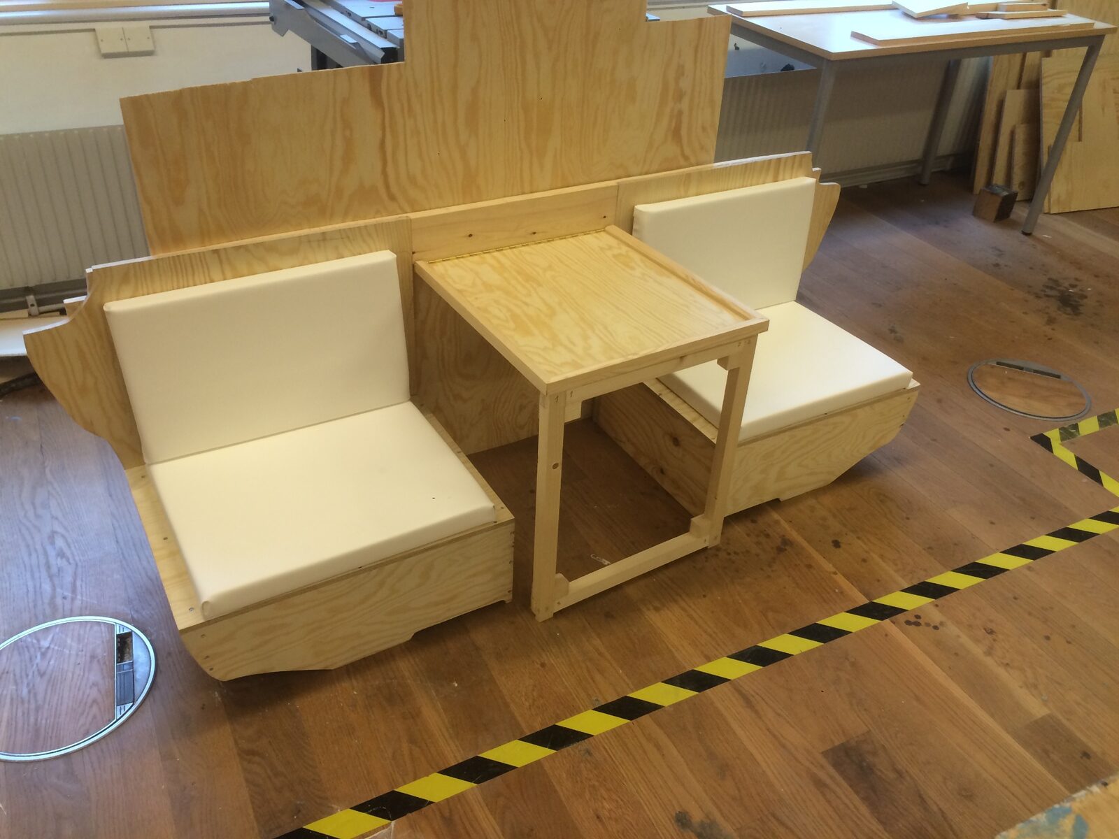 Sittgrupp i furu med två sitsar och ett integrerat bord under tillverkning