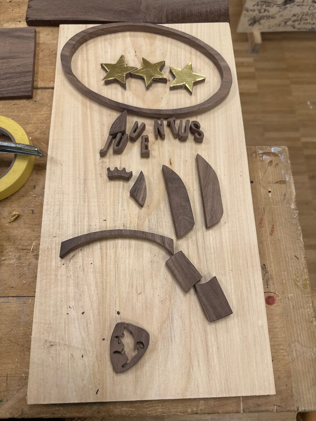 Juventus-loggan under tillverkning, lösa delar i valnöt och björk