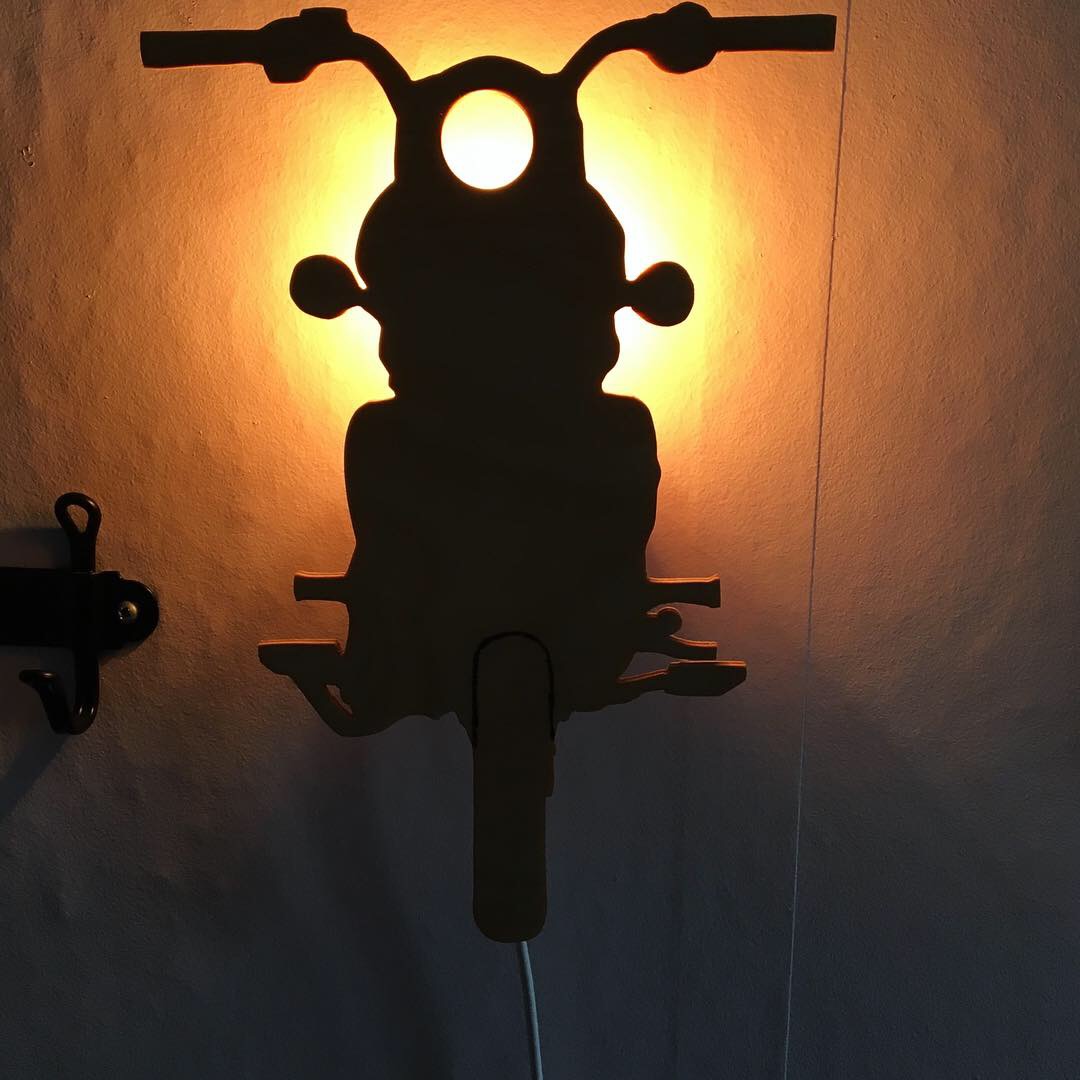 Motorcykelsilhuett i björk monterad som vägglampa