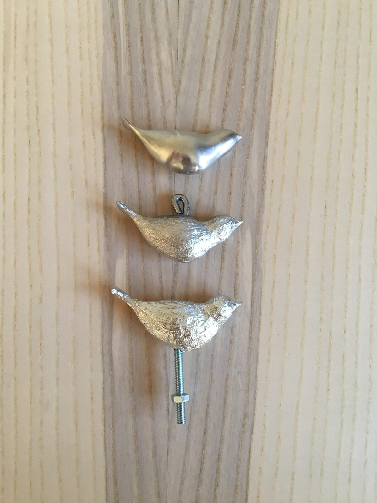 Tre små handgjutna tennfåglar monterade på platta i ask