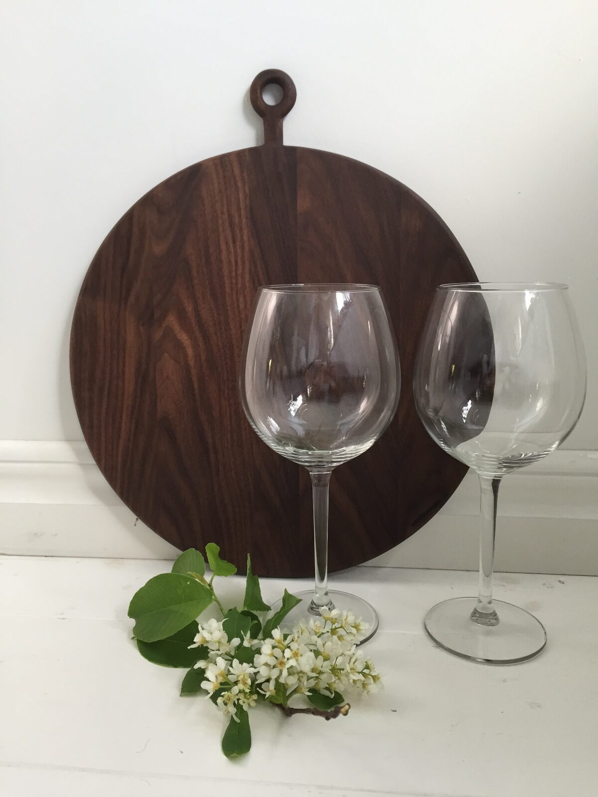 Rund serveringsbricka i valnöt med två vinglas framför