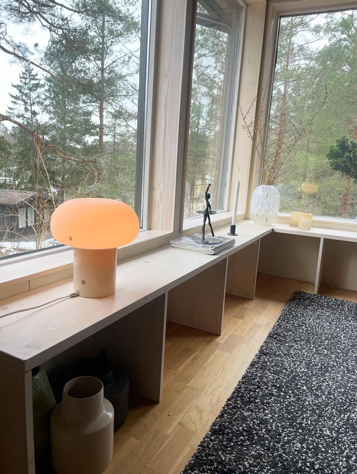 Specialbyggd bänk i furu längs fönsterrad med skogsutsikt